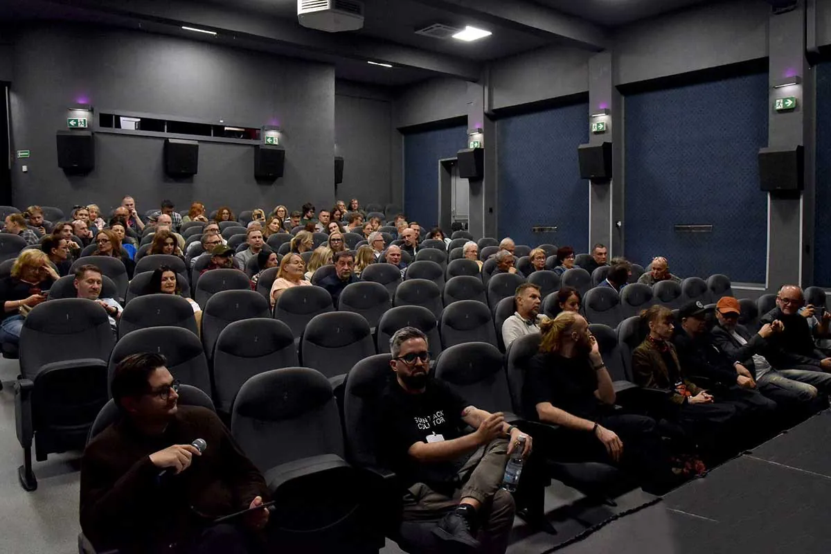 A guest with a microphone speaking to the audience in the cinema hall