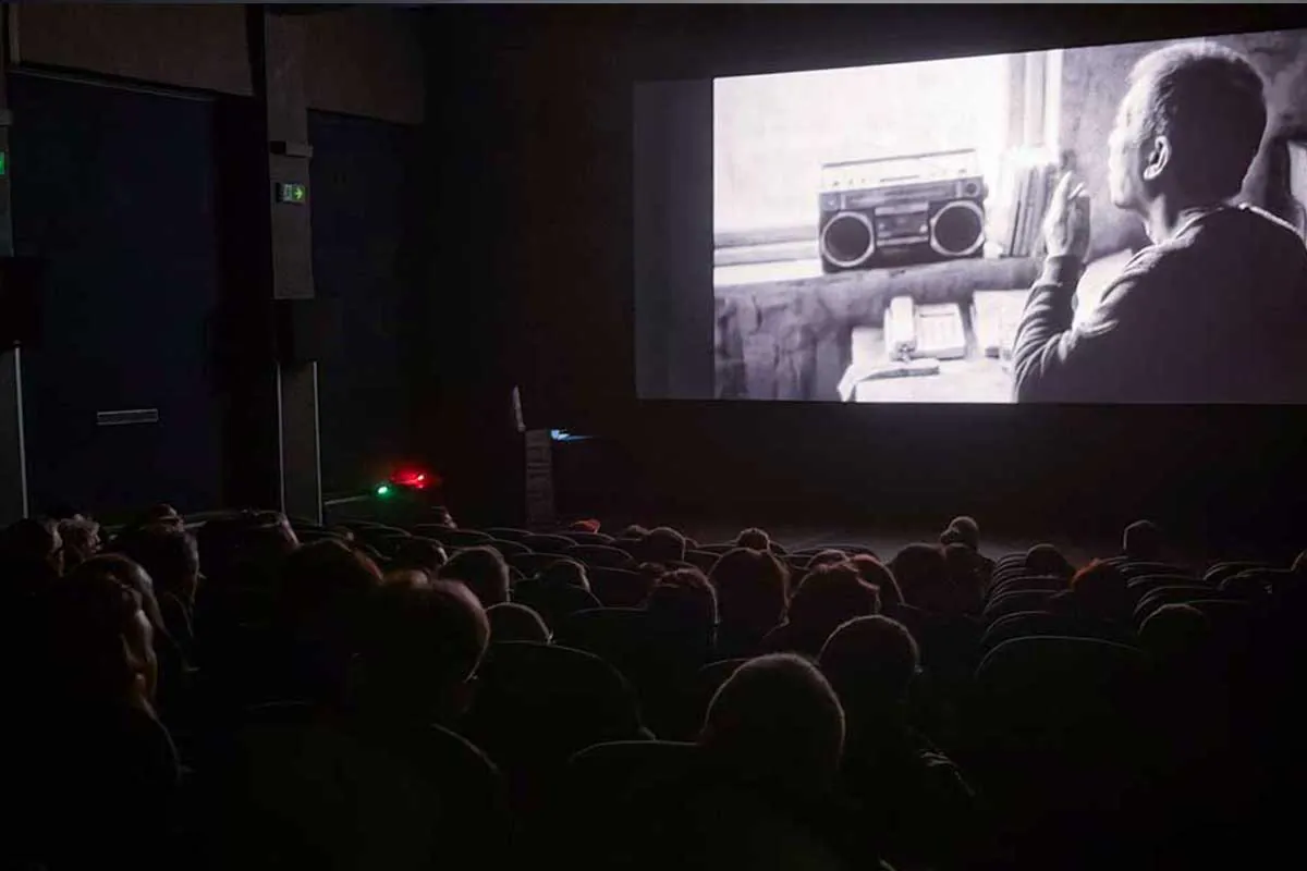 The audience watching a black-and-white film in the cinema hall